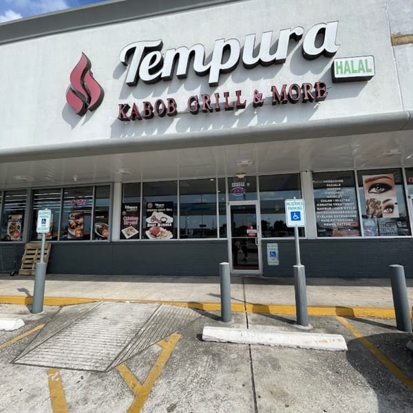 Exterior of Tempura Halal Indo-Pak Grill, a restaurant with a gray facade and large windows.